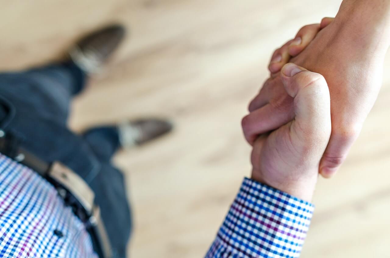 a landlord in a blue shirt shakes their tenants hand